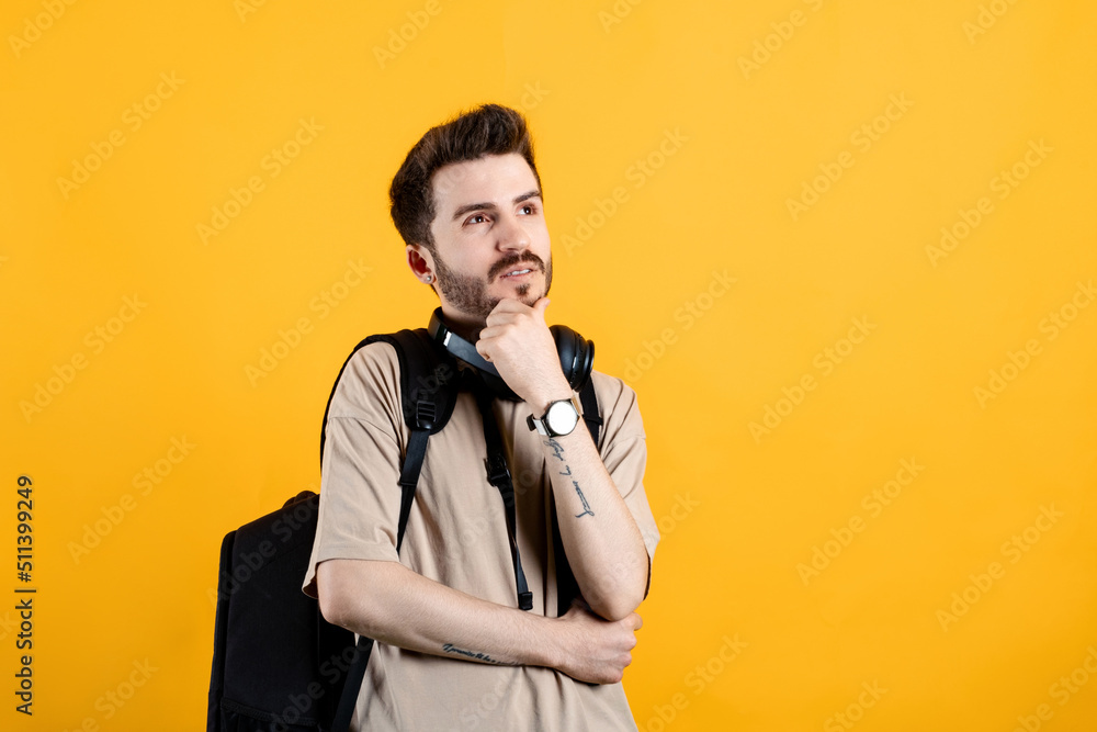 Young man wearing beige t-shirt posing isolated over yellow background serious face thinking about question, very confused idea Young man wearing beige t-shirt posing isolated over yellow background serious face thinking about question, very confused idea