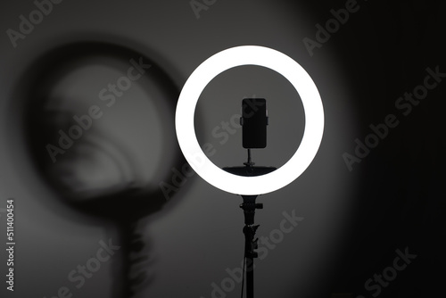 Led light blogger. Ring lamp with telephone in center on gray background. 