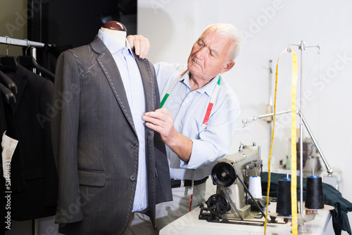 Experienced tailor tries on a new jacket on a mannequin in a sewing atelier