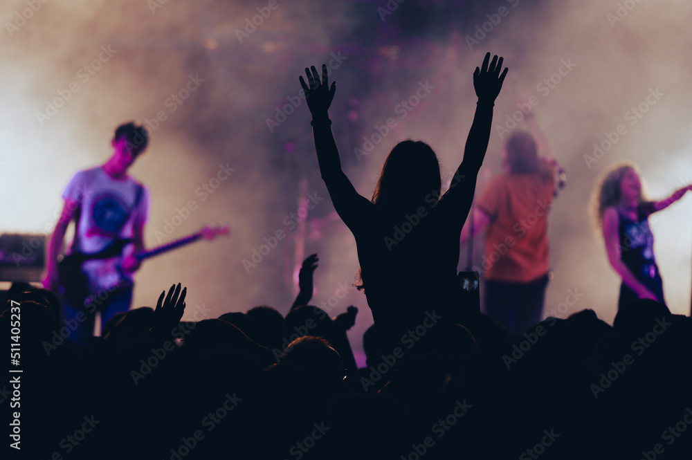 Silhouette of a woman with raised hands on a concert