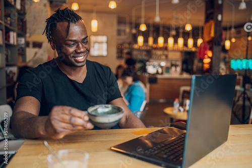 African american man using laptop while drinking coffee in a cafe © Zamrznuti tonovi