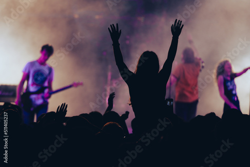 Silhouette of a woman with raised hands on a concert