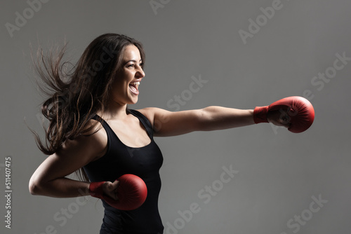 beautiful girl exercising karate punch and screaming against gray background. . © Nikola Spasenoski