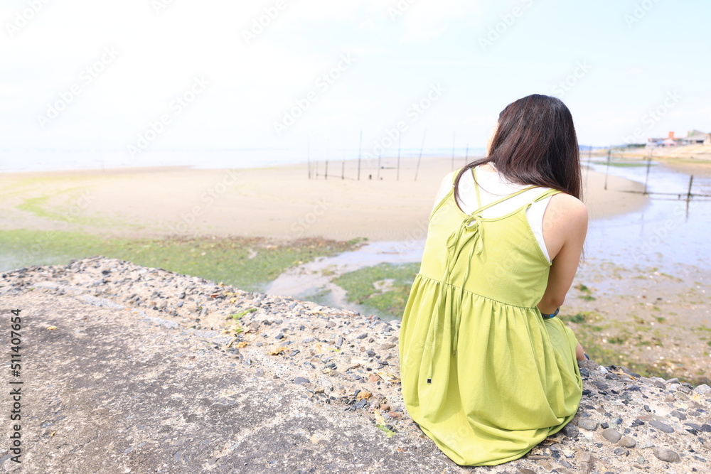 堤防で一人海を眺める女性