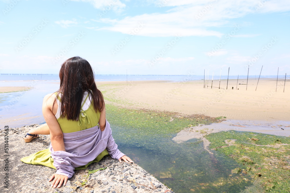 堤防で一人海を眺める女性