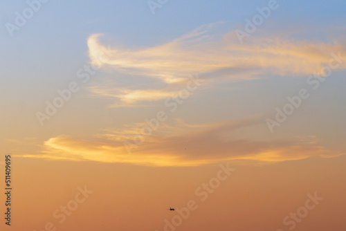 Sunset sky with clouds and airplane in the distance