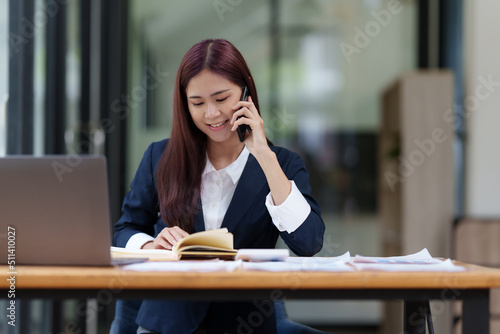 Image of Happy Asian Business woman discussing with her business partner by cell phone. Finance and brainstorm concept.