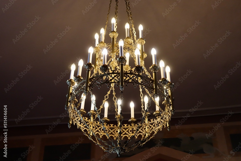 Splendid candelabra with multiple branches, interior detail in luxorious historic hall, electric light bulbs in shape of candles, brass, crystal