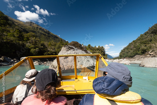 Jet boating on the Waiatoto River surrounded by large rocks and thick rainforest, on a sunny day. West Coast, New Zealand. photo