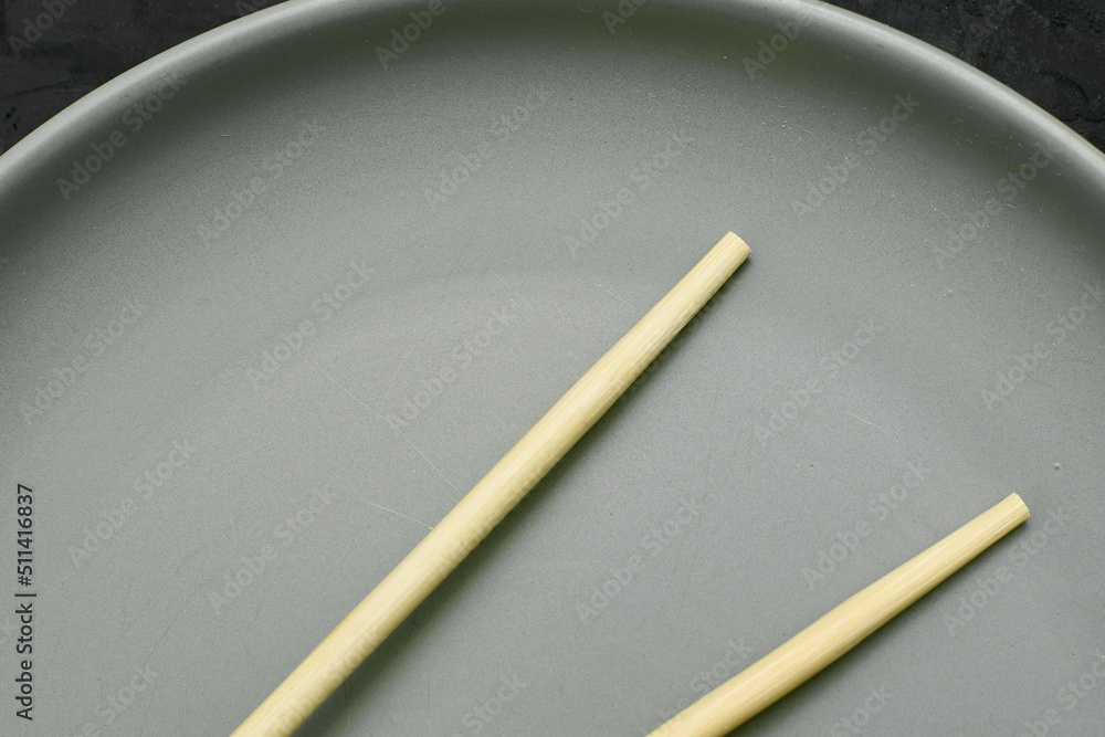 grey plate and chopsticks on a black background grey plate and chopsticks on a black background