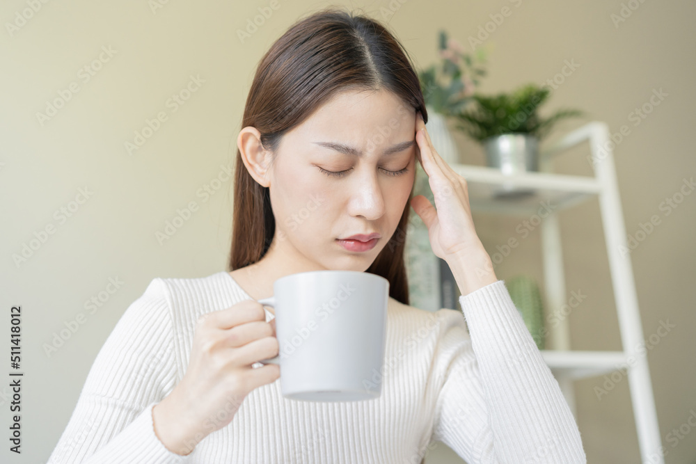 Fatigue, tension asian young woman having headache, migraine after drinking caffeine of coffee or tea while working, using laptop computer, face expression stress. Depression, illness at home office. Fatigue, tension asian young woman having headache, migraine after drinking caffeine of coffee or tea while working, using laptop computer, face expression stress. Depression, illness at home office.
