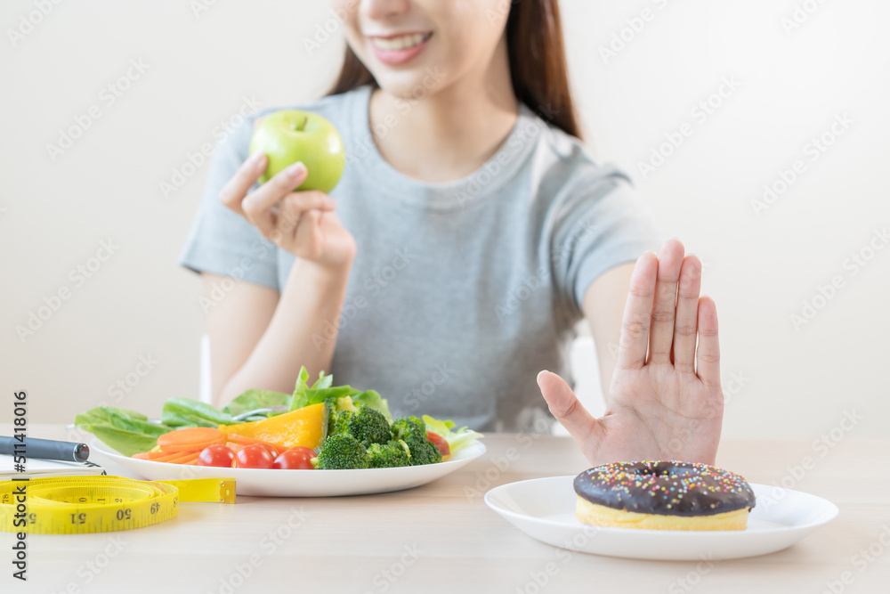 Diet, Dieting asian young woman or girl use hand push out, deny sweet donut and choose green salad vegetables, eat food for good healthy, health when hungry. Close up female weight loss person. Diet, Dieting asian young woman or girl use hand push out, deny sweet donut and choose green salad vegetables, eat food for good healthy, health when hungry. Close up female weight loss person.
