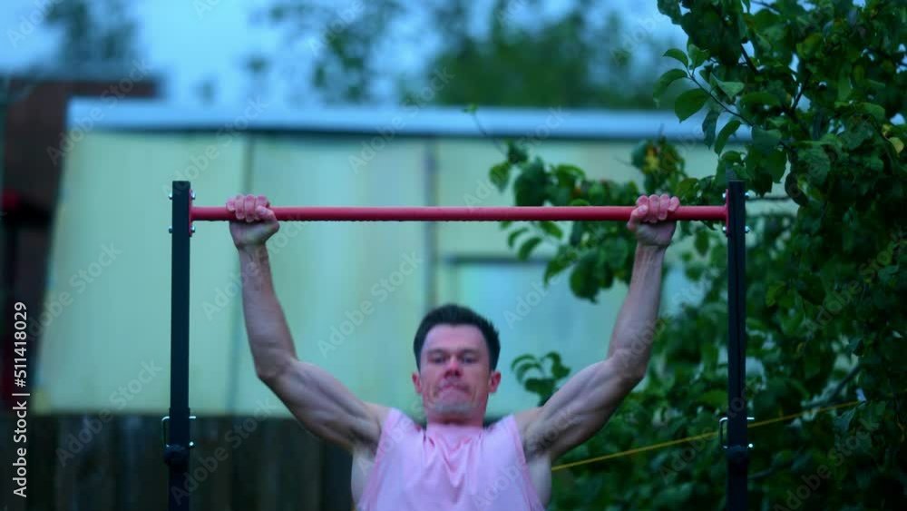 A Muscular Young Man Doing Pull-Ups Exercise On The Horizontal Bar Outdoors In Lithuania. - Medium Shot A Muscular Young Man Doing Pull-Ups Exercise On The Horizontal Bar Outdoors In Lithuania. - Medium Shot