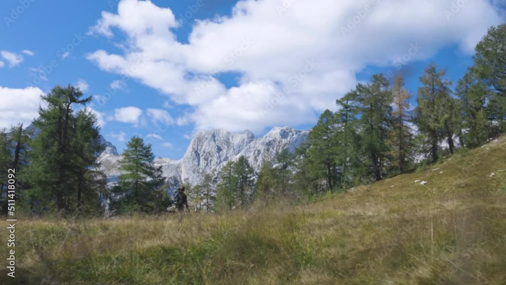 Backpacker Goes Towards Mountain Peak, Low Angle View with Sky in Background Backpacker Goes Towards Mountain Peak, Low Angle View with Sky in Background