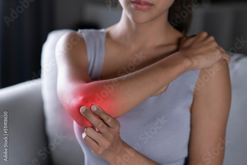 Young Asian woman wearing casual clothes having pain in his elbow. A young woman touching her painful elbow. Health care and medical concept.