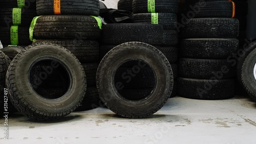 The tire rolls through the warehouse with tires. The tire stops on another tire