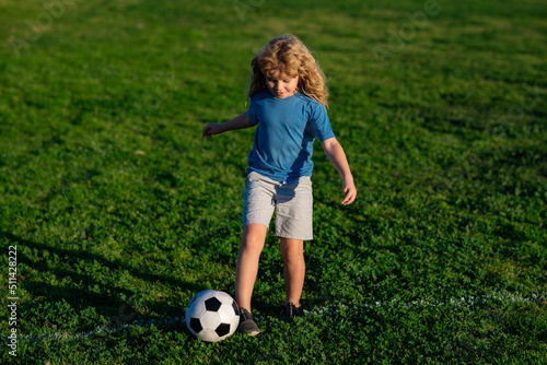 Soccer child play football. Kid kicking a football ball on a grass. Sports kid during soccer training.
