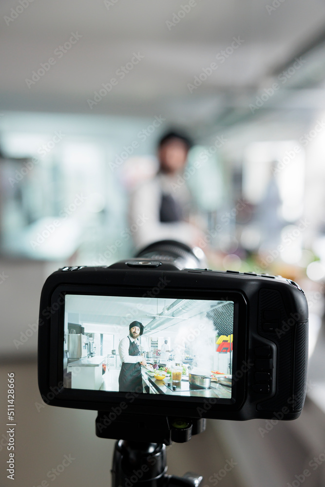Close up of camera filming gastronomy expert cooking vegetable dish for online culinary school course. Head chef cooking tasty food while vlogging process in restaurant professional kitchen. Close up of camera filming gastronomy expert cooking vegetable dish for online culinary school course. Head chef cooking tasty food while vlogging process in restaurant professional kitchen.