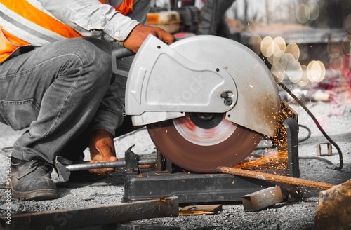 Fototapeta Naklejka Na Ścianę i Meble -  Construction worker cutting steel rebar with power cutting machine. 