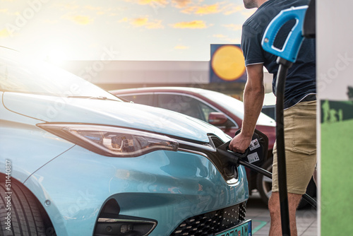 Powering electric car on a charger in a public parking lot.