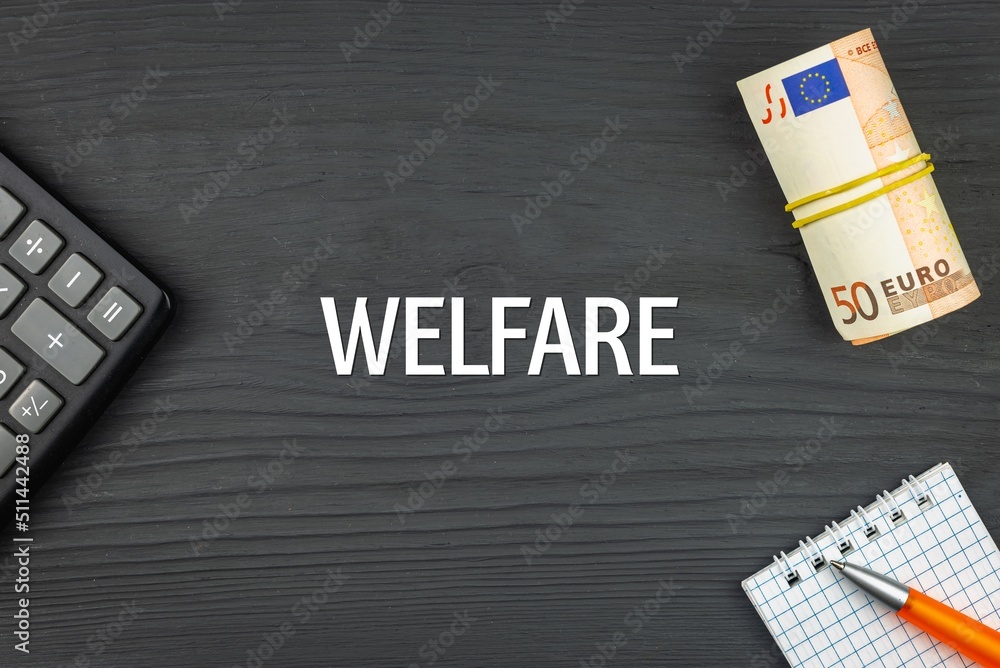 WELFARE - word (text) and euro money on a wooden background, calculator, pen and notepad. Business concept (copy space).