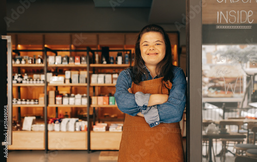 Foto Cheerful woman with Down syndrome standing at the door of a deli