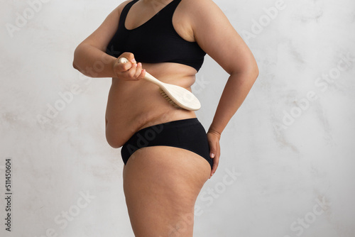 Cropped overweight  adipose female rubbing fold back  side skin  using stiff exfoliating brush  anti cellulite dry lymph massage against visceral excess fat. Spa procedure. Health  body care  beauty