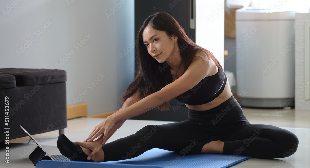 Attractive sporty woman stretching leg before workout in bright living room. Sport, fitness and healthy lifestyle concept.