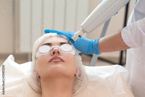 Laser Procedures Ideas. Caucasian Woman Getting Cosmetology Laser Facial Beauty Treatment While Removing Pigmentation in Clinic Using Intense Pulsed Light Therapy IPL