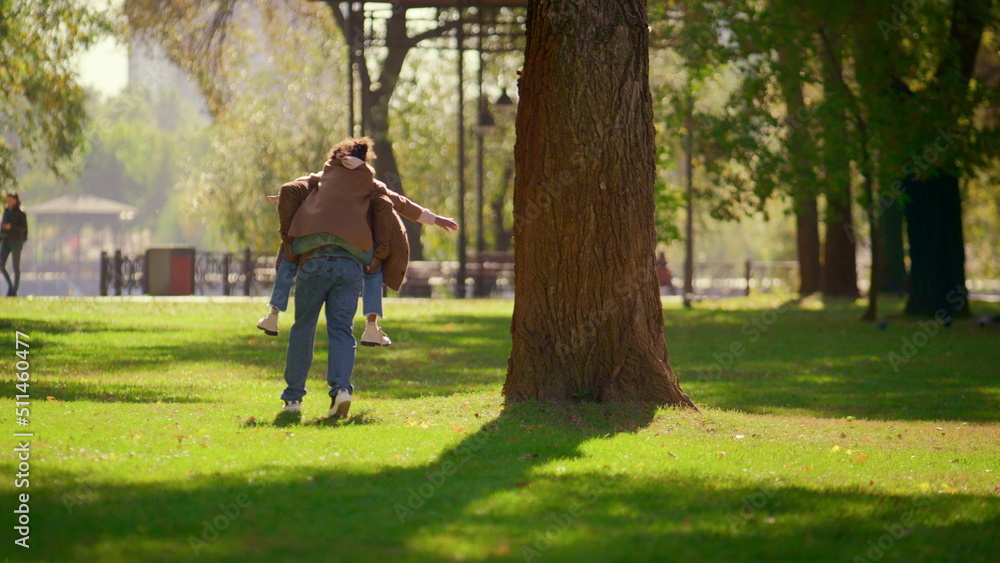 Happy parent piggybacking daughter in sunny spring park. Loving father weekend. Happy parent piggybacking daughter in sunny spring park. Loving father weekend.