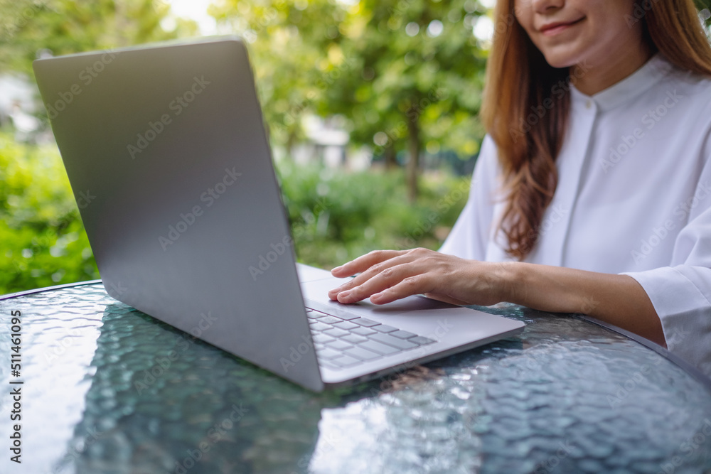 Closeup image of a businesswoman working and typing on laptop computer keyboard in the outdoors Closeup image of a businesswoman working and typing on laptop computer keyboard in the outdoors