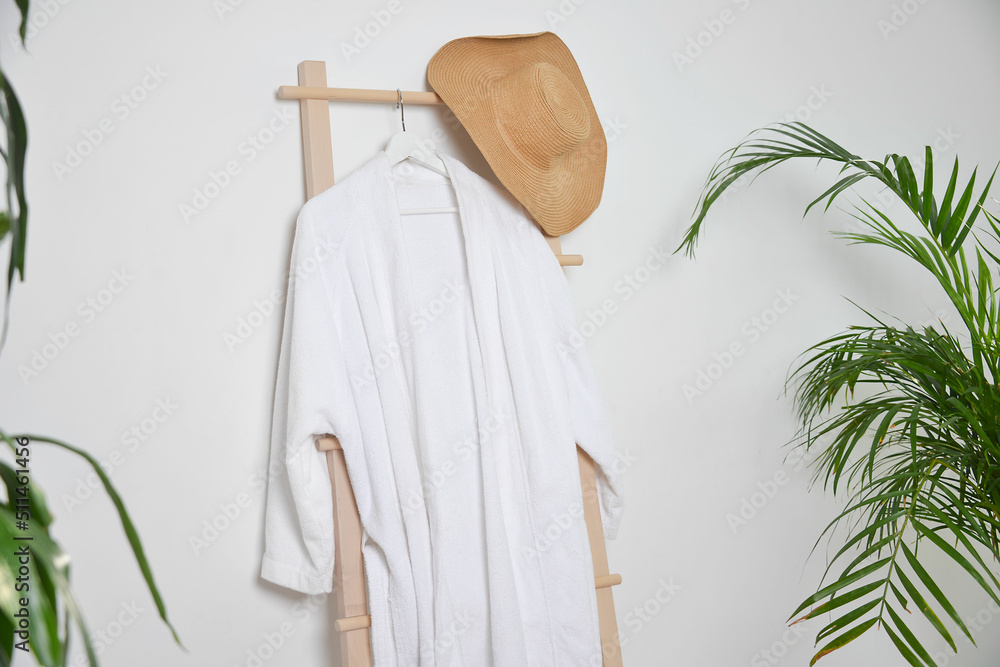 Closeup view of a clean white bathrobe hanging on rack indoors and