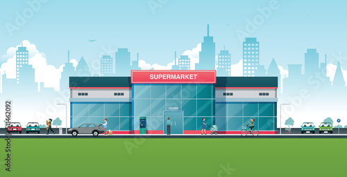 A supermarket with people and cars roaming with the city in the background.
