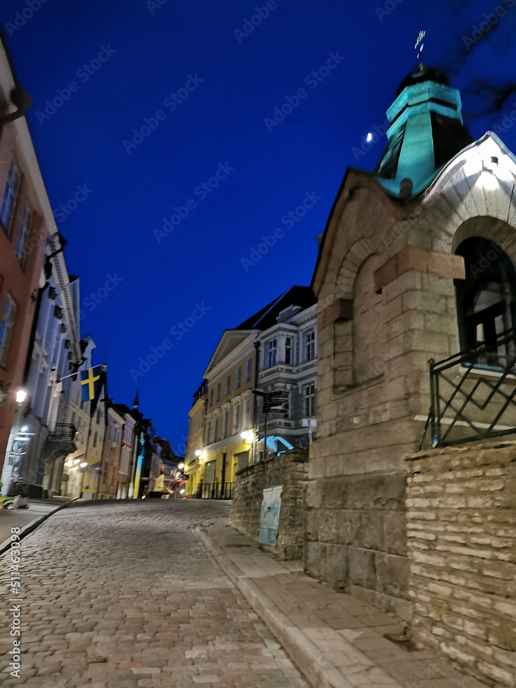 Old paved narrow street of Old Tallinn with a small chapel against the blue sky. Spring evening.