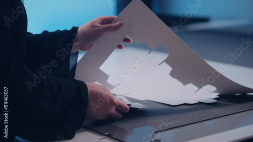 An employee in a factory assembles packaging from cut-out paper.