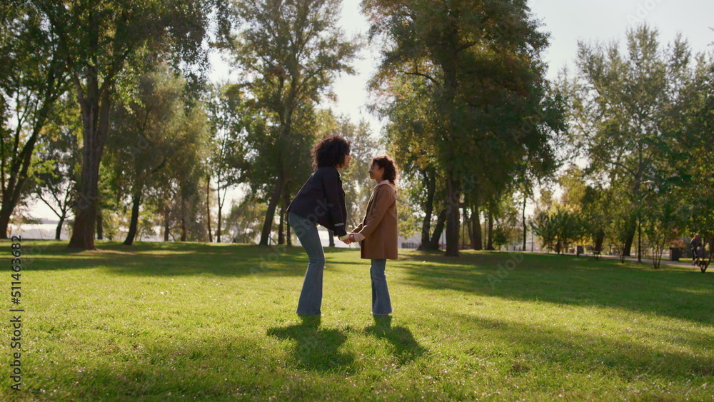 Mother holding daughter hands gently touching noses on sunny green park field. Mother holding daughter hands gently touching noses on sunny green park field.