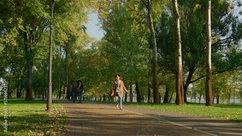 Fototapeta Naklejka Na Ścianę i Meble -  Happy family walking park together on sunny warm evening. Joyful girl jumping