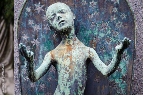 La statua di bronzo ossidato di un bambino circondato dalle stelle sopra una tomba del cimitero monumentale di Milano photo