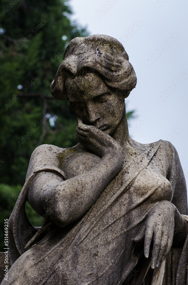 La statua di una donna sofferente sopra una tomba del cimitero monumentale di Milano