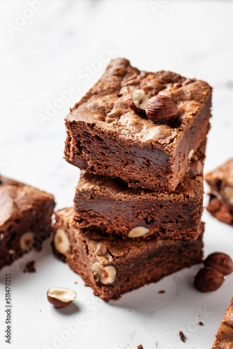 Stack of delicious brownie pieces with hazelnuts on marble background  close up