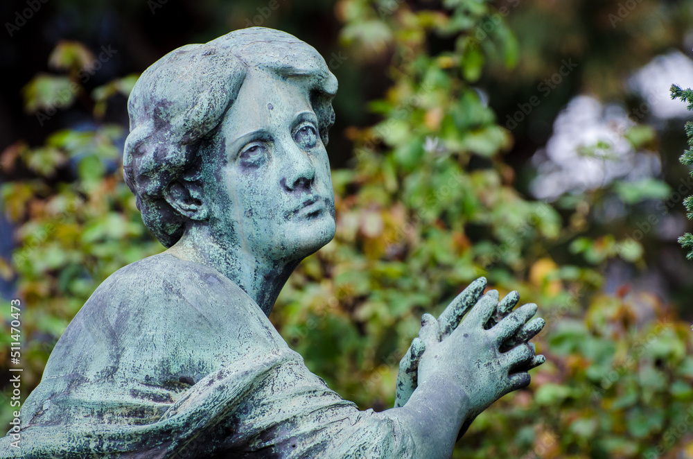 Il volto di bronzo ossidato di una donna sofferente sopra una tomba del cimitero monumentale di Milano