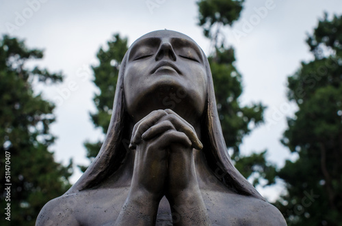 La statua di una donna disperata che prega su una tomba del cimitero monumentale di Milano photo