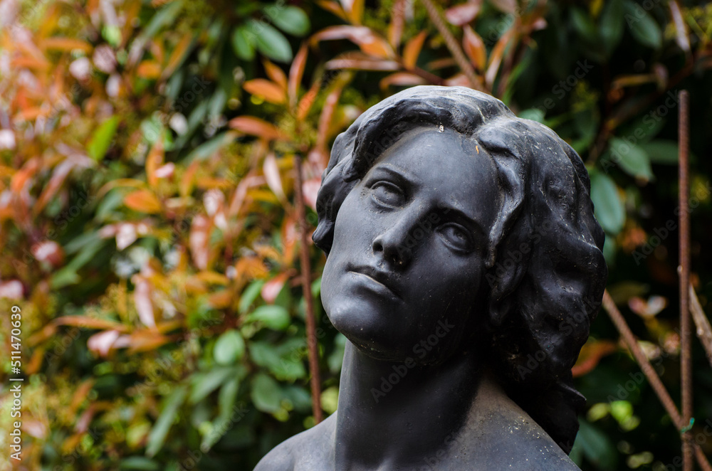 Primo piano della statua di una donna disperata su una tomba del cimitero monumentale di Milano con un cespuglio sullo sfondo Primo piano della statua di una donna disperata su una tomba del cimitero monumentale di Milano con un cespuglio sullo sfondo