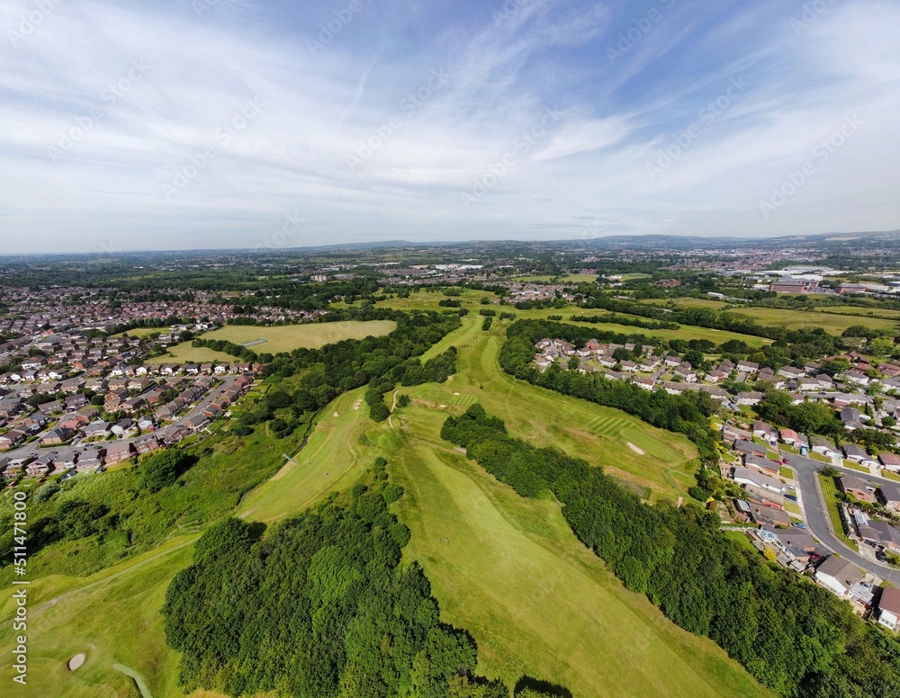 Aerial view looking down onto a golf course surrounded by houses and buildings. 