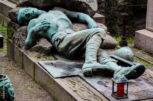 La statua di bronzo ossidato di un soldato morto che giace su una tomba del cimitero monumentale di Milano