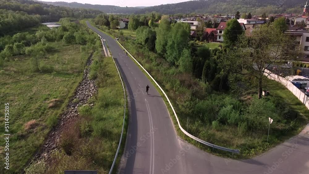 man roller skating on empty road, sunset, cinematic aerial shot man roller skating on empty road, sunset, cinematic aerial shot