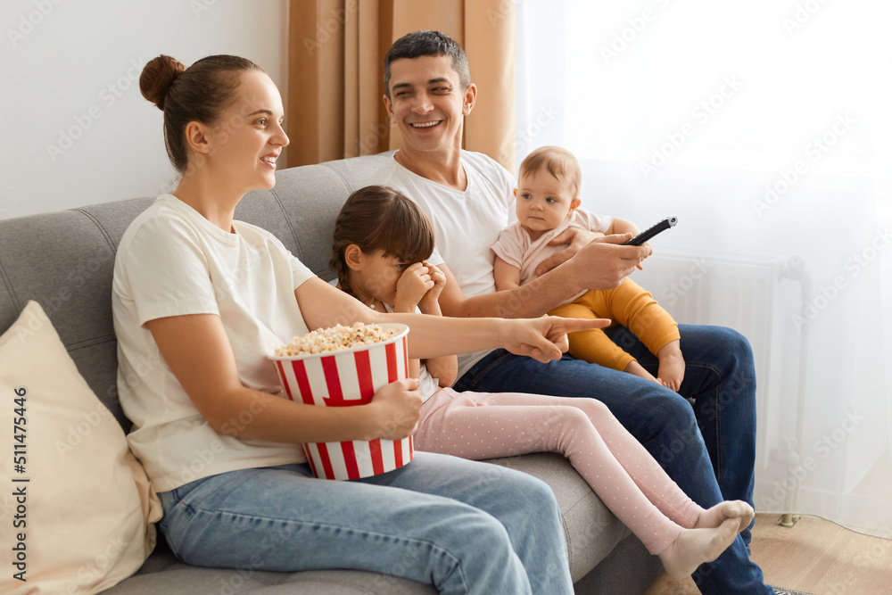 Side view of happy family watching television while eating popcorn