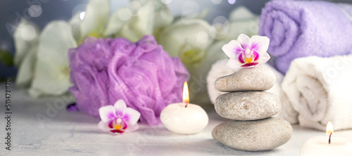 banner with massage stones  burning candles  rolled towels  flowers  abstract lights. Spa resort therapy composition in lilac colors Soft focus