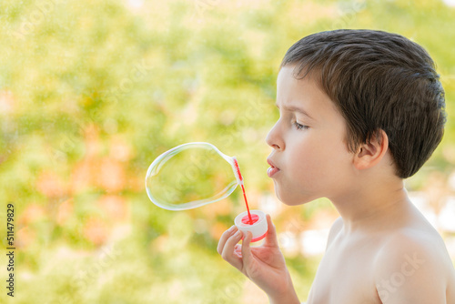 Little boy blowing bubbles in field with copy space.