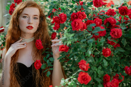 Wallpaper Mural Beautiful redhead freckled woman with long curly hair, red lips makeup, wearing elegant pearl necklace, vintage dress, posing in rose garden. Copy, empty space for text Torontodigital.ca